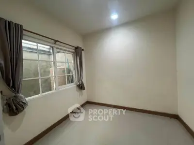Spacious unfurnished room with large window and neutral walls, perfect for customization.