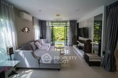 Spacious living room with modern decor and large windows overlooking greenery.