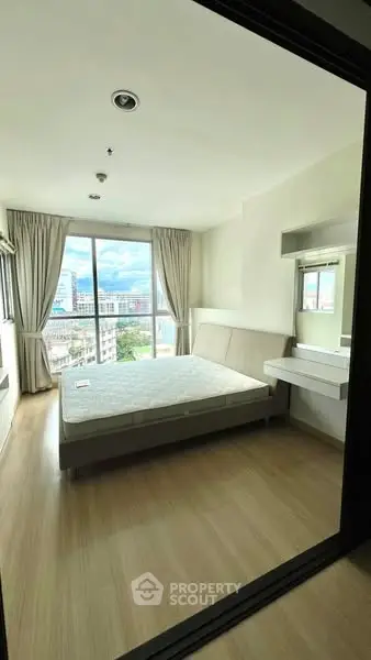Bright bedroom with city view and modern furnishings in high-rise apartment.