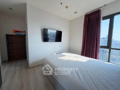 Modern bedroom with large window and wall-mounted TV in a high-rise apartment.