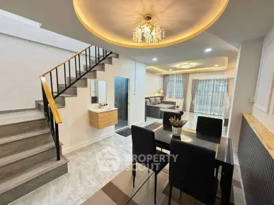 Modern open-plan living and dining area with elegant staircase and stylish lighting.