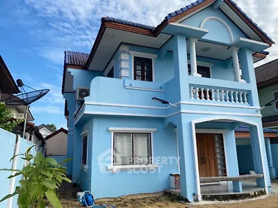 Charming blue two-story house with balcony and classic architectural details.
