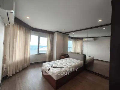 Spacious bedroom with large windows and mirrored closet in modern apartment.