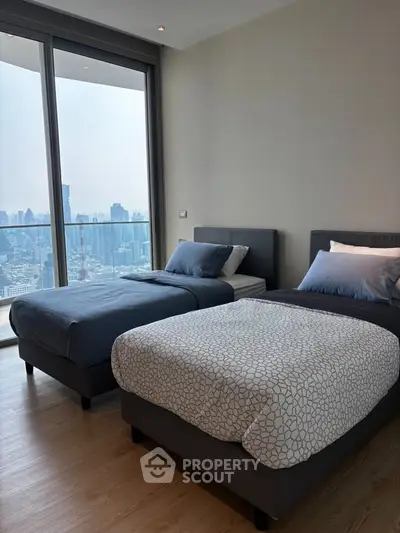 Modern bedroom with twin beds and stunning city view from large windows.