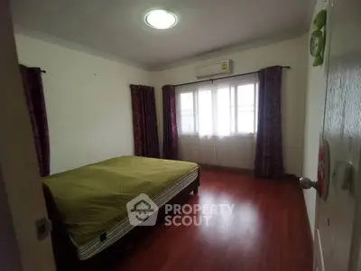 Spacious bedroom with wooden flooring and natural light