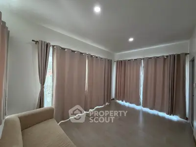 Spacious living room with large windows and elegant curtains, perfect for natural light and cozy gatherings.