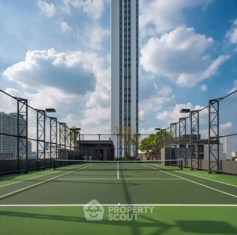 Stunning rooftop tennis court with cityscape views and modern high-rise backdrop.
