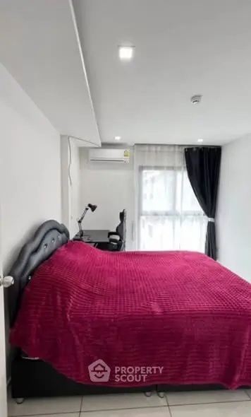 Modern bedroom with vibrant red bedding and sleek furniture in a well-lit space.