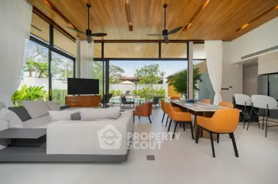 Luxurious open-plan living room with modern furniture and pool view, featuring high ceilings and elegant decor.