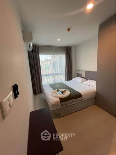 Cozy bedroom with modern decor and large window offering natural light.