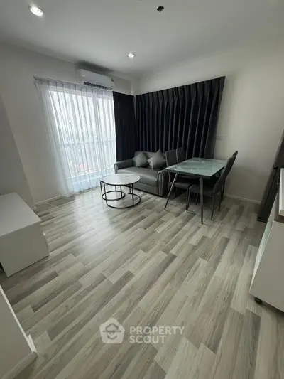 Modern living room with sleek furniture and large window offering natural light.