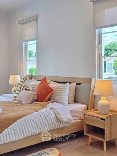 Cozy bedroom with modern decor and natural light from large windows.