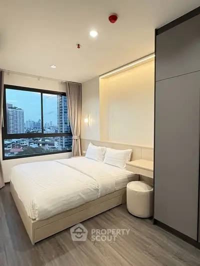 Modern bedroom with city view, featuring a cozy bed and stylish decor in a high-rise apartment.