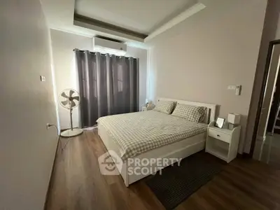 Cozy bedroom with modern decor, featuring a comfortable bed, stylish curtains, and wooden flooring.