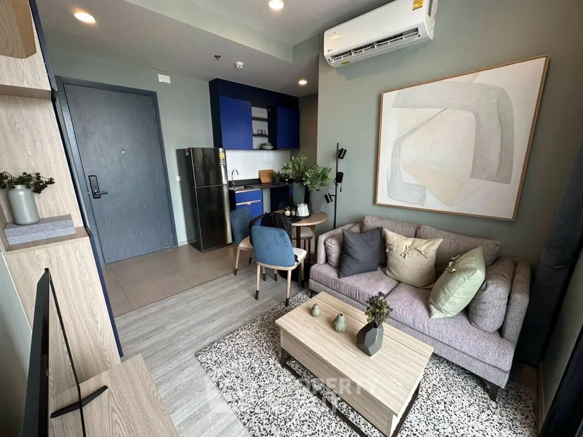 Modern living room with stylish decor and compact kitchen in open layout apartment.