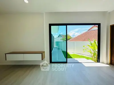 Modern living room with large sliding glass door opening to a sunny garden view.