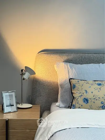 Cozy bedroom with stylish decor and soft lighting, featuring a modern lamp and elegant bedding.