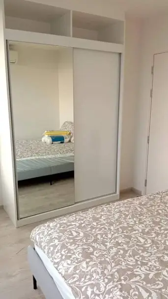 Modern bedroom with mirrored wardrobe and stylish bedding in a cozy apartment.