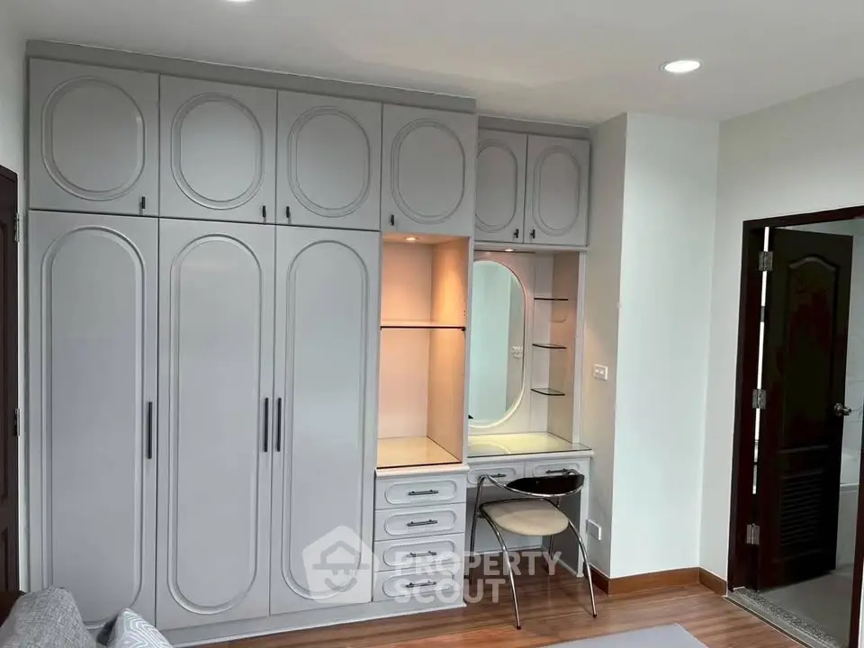 Elegant bedroom with built-in wardrobe and vanity in modern design.