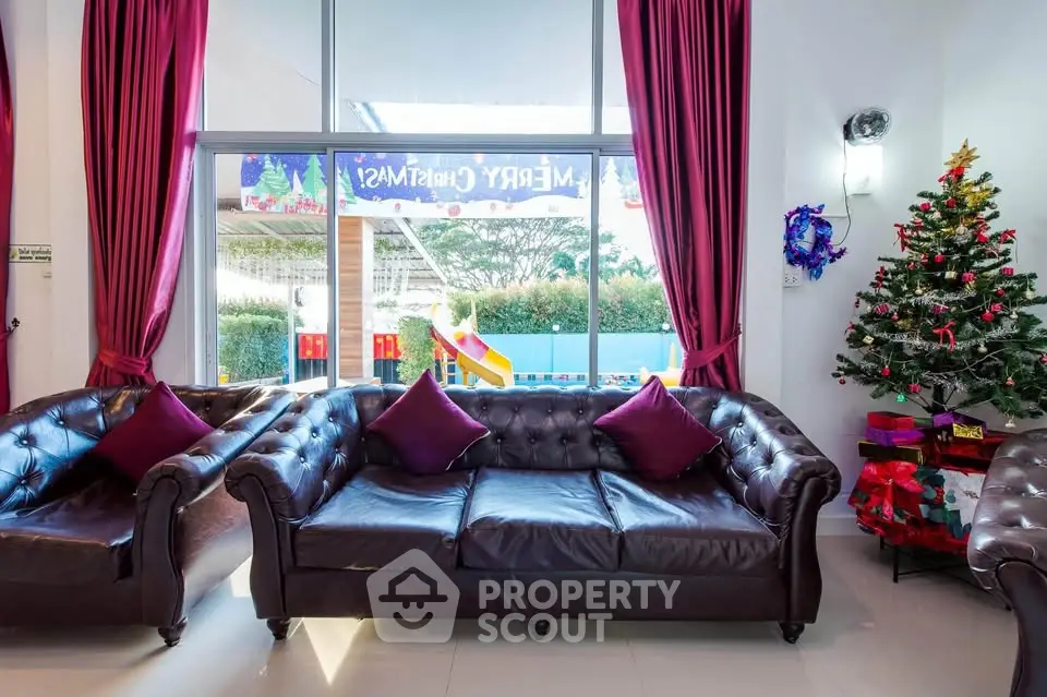 Festive living room with leather sofas and Christmas decor, overlooking a playground.