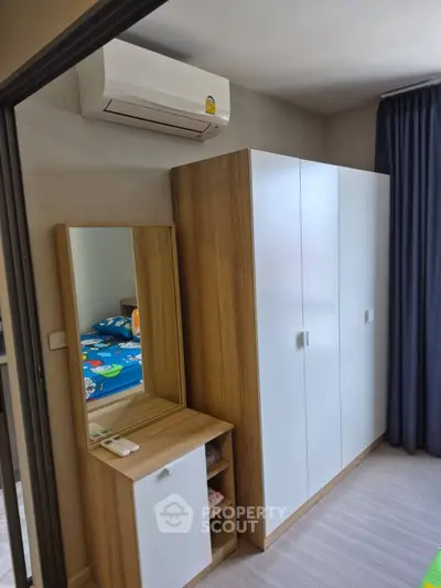 Modern bedroom with sleek wardrobe and air conditioning unit, perfect for comfortable living.