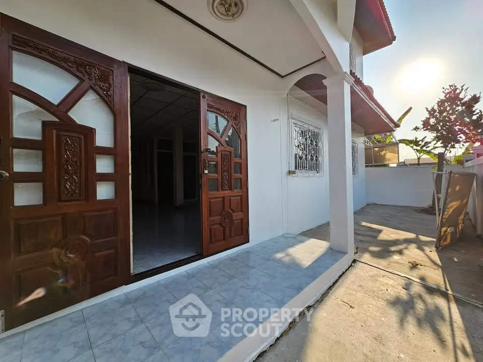 Charming single-story home with elegant wooden doors and spacious outdoor patio, perfect for enjoying sunny days.
