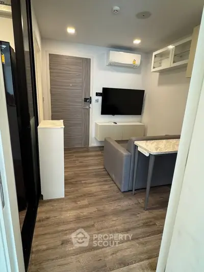 Modern living room with sleek design, featuring a wall-mounted TV, air conditioning, and stylish flooring.