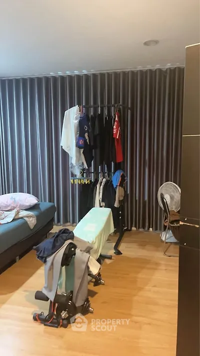 Cozy bedroom with clothes rack and ironing board, ideal for practical living.