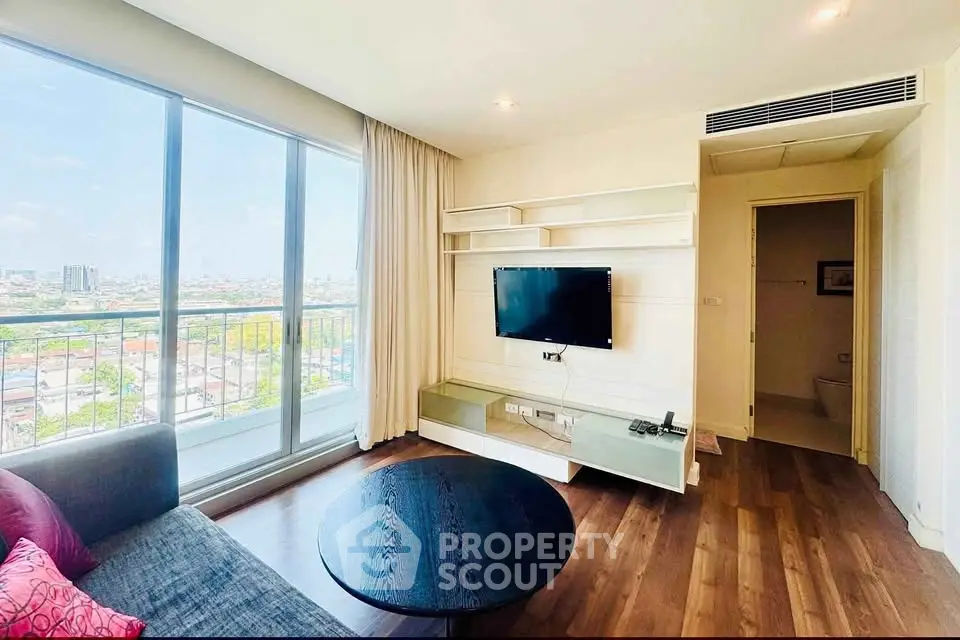 Modern living room with city view, featuring sleek TV setup and large windows for natural light.