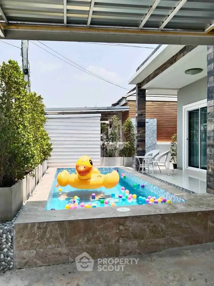 Charming outdoor pool with playful duck float and colorful balls in modern backyard setting.