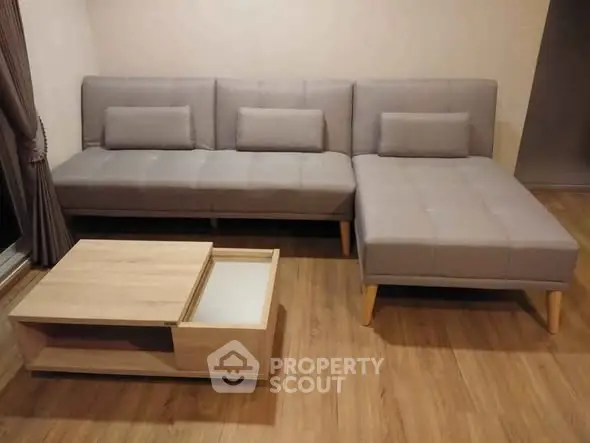Modern living room with stylish gray sectional sofa and wooden coffee table on hardwood floor.