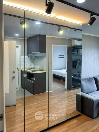 Modern apartment interior with mirrored wardrobe, cozy living area, and sleek kitchen design.