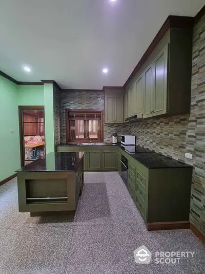 Spacious modern kitchen with green cabinetry and sleek countertops