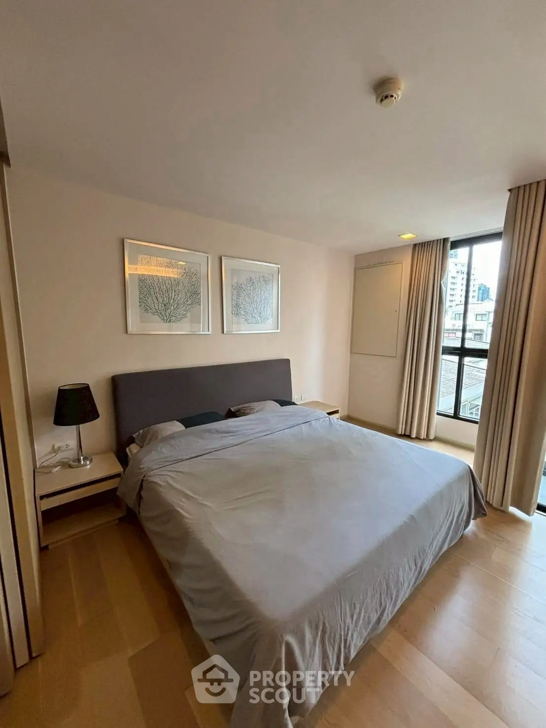 Spacious bedroom with modern decor and large window offering city view