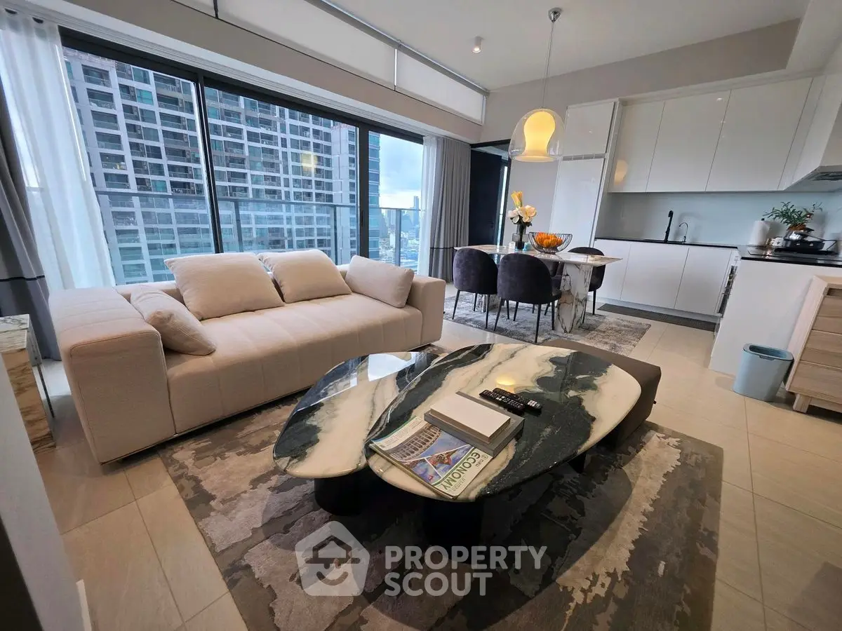 Modern living room with open kitchen and city view, featuring stylish furniture and elegant decor.