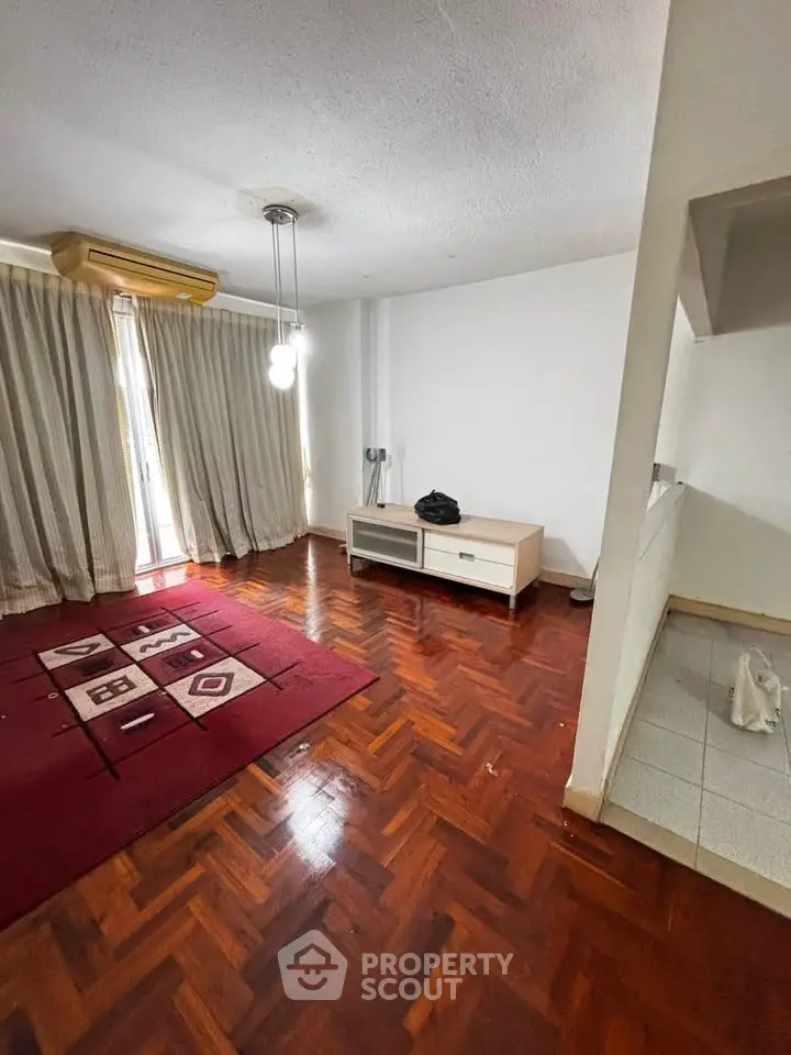 Spacious living room with wooden flooring and natural light, perfect for cozy gatherings.