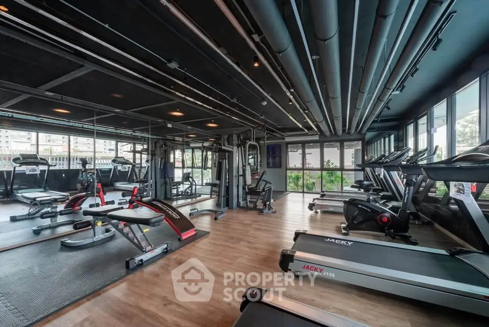 Modern gym with state-of-the-art equipment and panoramic windows in luxury residential building.
