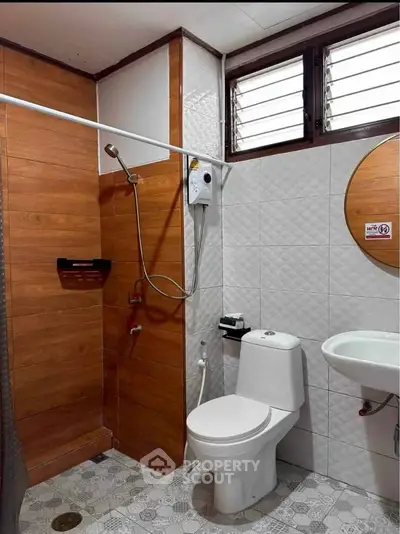 Modern bathroom with wood paneling, shower, and sleek fixtures in a stylish real estate property.