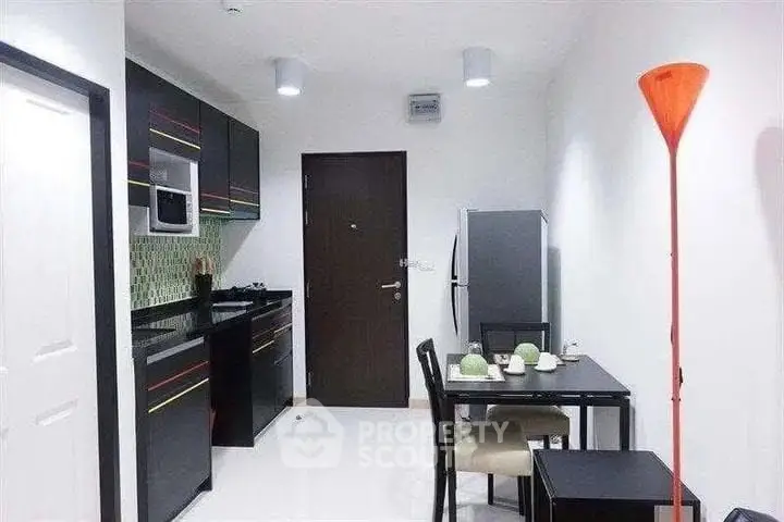 Modern kitchen with sleek black cabinets and dining area in a stylish apartment.