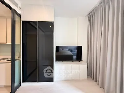 Modern living room with sleek TV stand and sliding glass door to kitchen