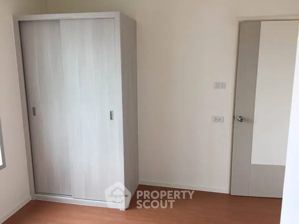 Minimalist bedroom with wooden wardrobe and door, showcasing simple elegance.