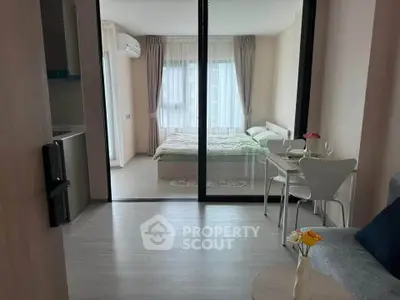 Modern studio apartment with glass partition, cozy bedroom, and stylish dining area.