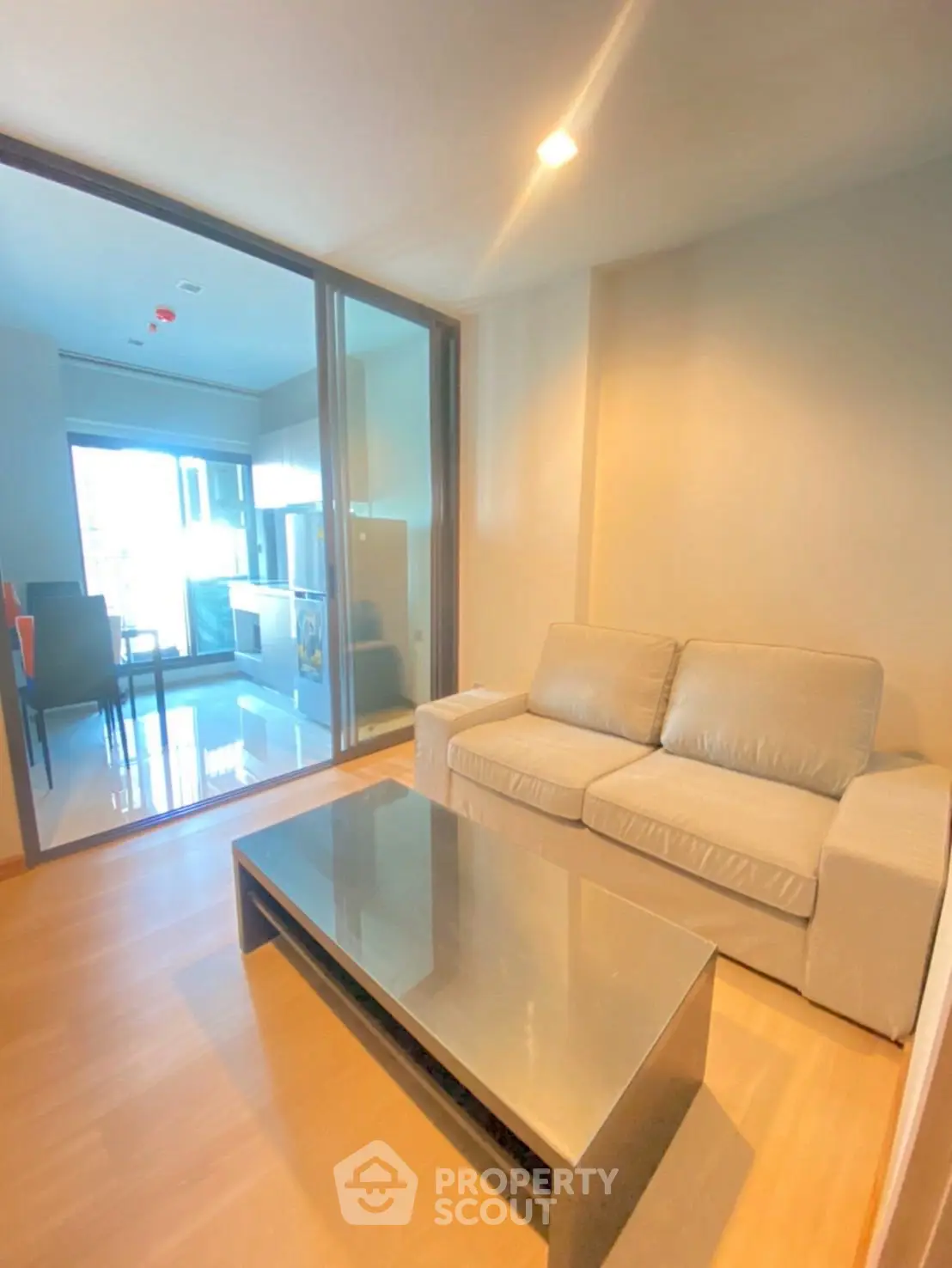 Modern living room with cozy sofa and sleek coffee table, open layout leading to kitchen area.