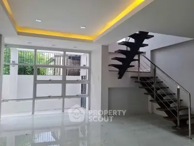 Modern interior with sleek staircase and large windows in a spacious living area.
