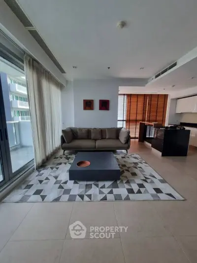 Modern living room with stylish sofa and geometric rug in open layout apartment.