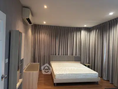 Spacious bedroom with modern decor and ample natural light, featuring a comfortable bed and stylish furnishings.
