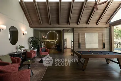 Luxurious living room with pool table and modern decor, featuring high wooden ceilings and stylish furniture.