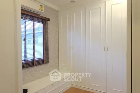 Spacious walk-in closet with elegant white cabinetry and natural light.