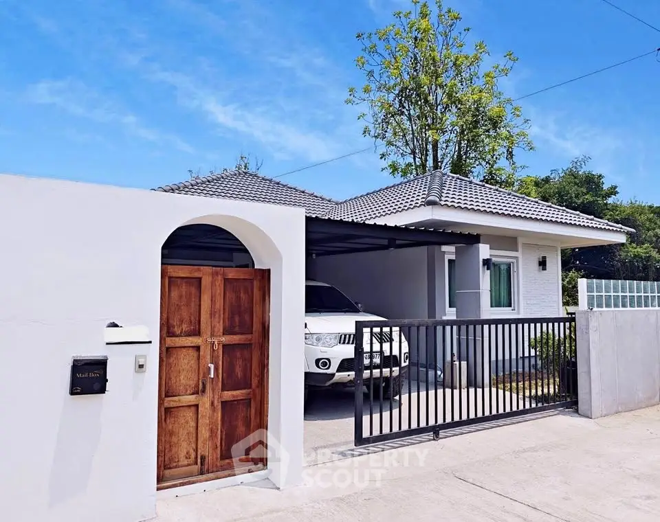 Charming single-story home with gated driveway and lush greenery.