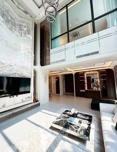 Luxurious modern living room with high ceilings, marble accents, and elegant chandelier in a spacious open layout.